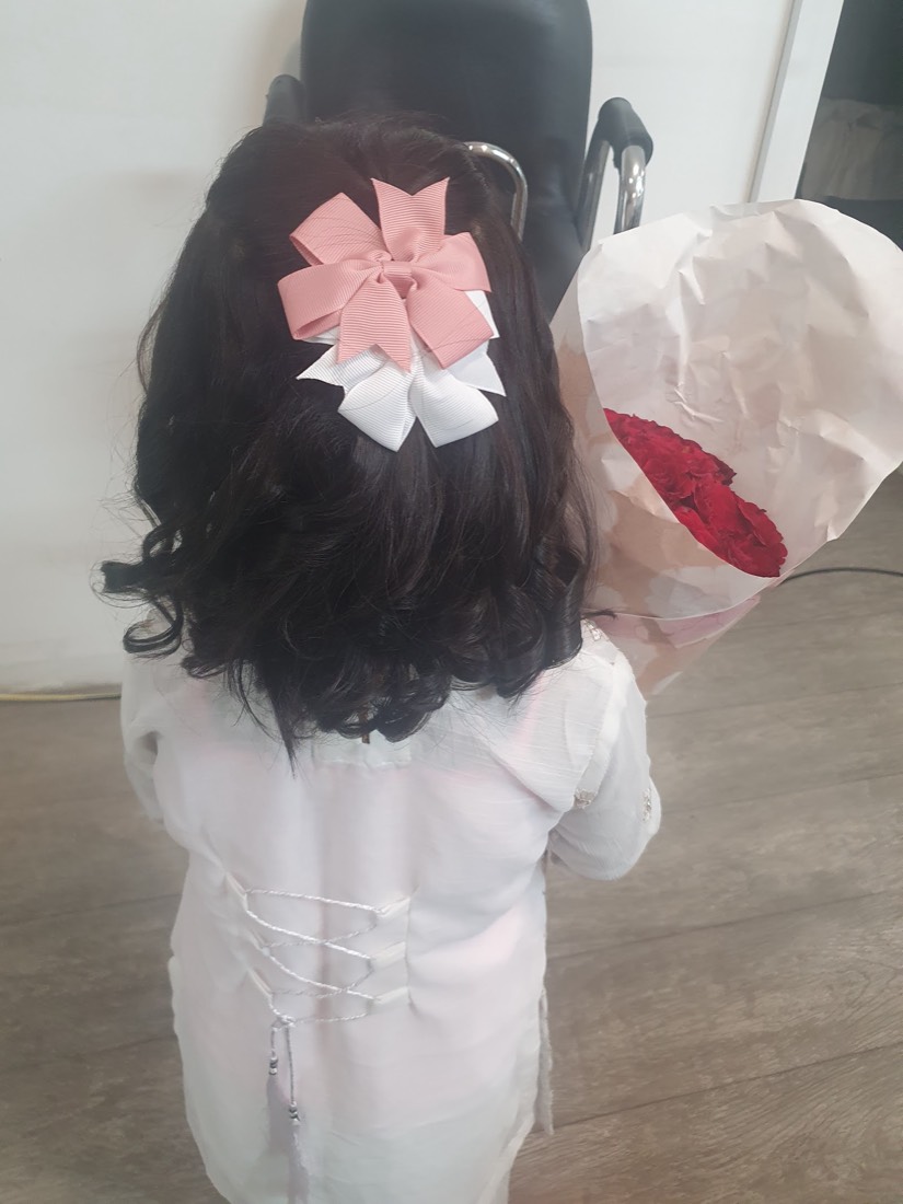 A little one's hair curled and dressed with pink and white bows