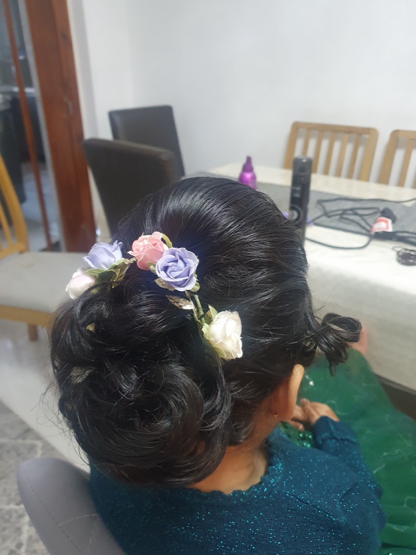 A low occasion updo finished with a pastel floral hairpiece